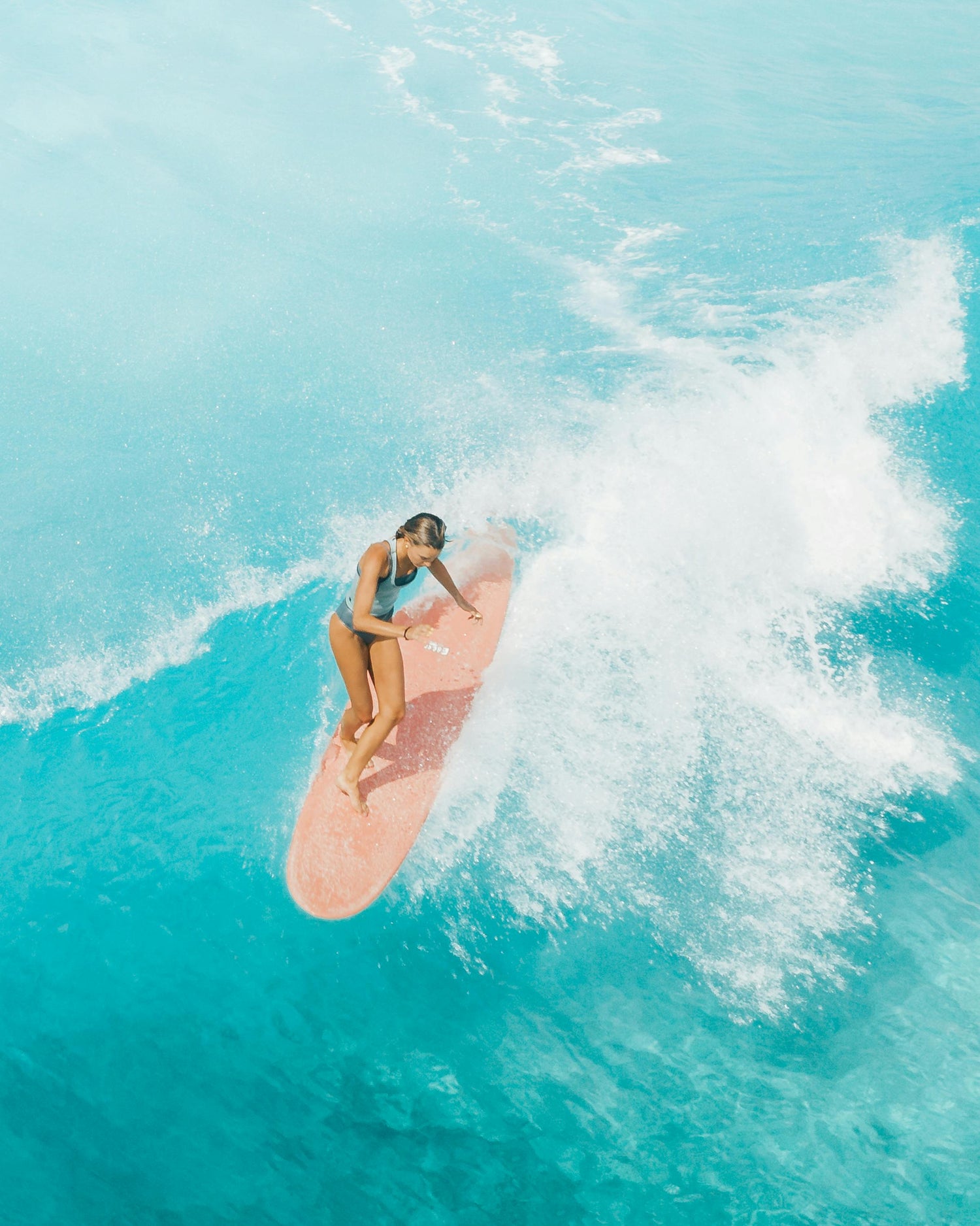 Christine Cole surfing on a surfboard, showcasing her connection to the ocean, founder of Mālie the label