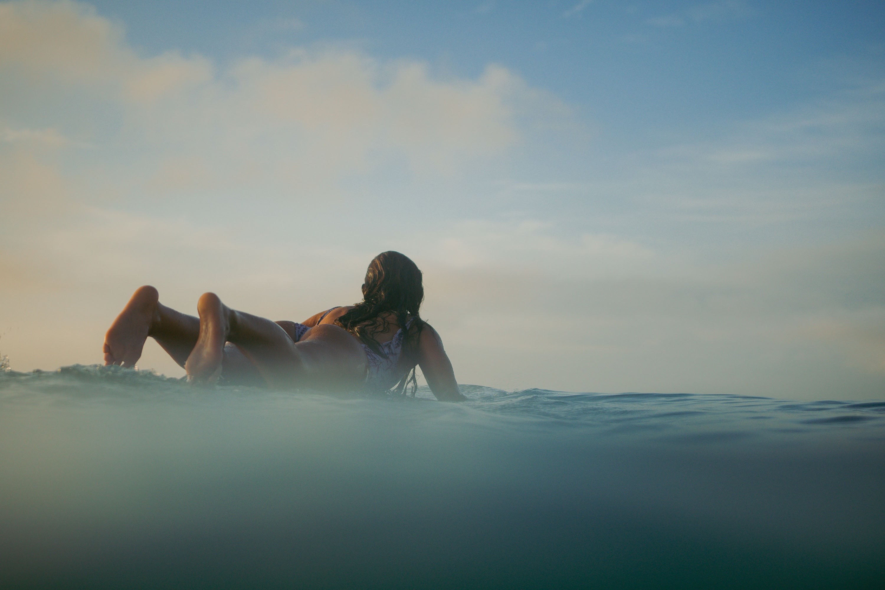 Model paddling in the ocean, showcasing eco-conscious swimwear by Mālie the label